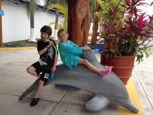 boy and girl sitting on dolphin statue