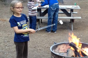Little girl roasts marshmallows at campfire