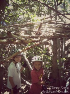 kids building fort in the forest out of wood and branches