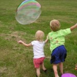 Kids chase a bubble at a park